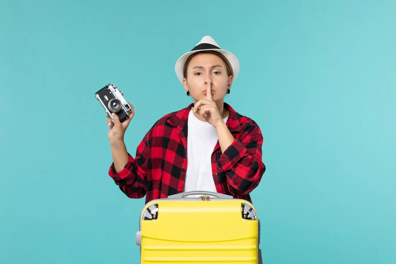 Фронтальный вид молодой женщины, отправляющейся в путешествие и держащей камеру, на синем фоне.